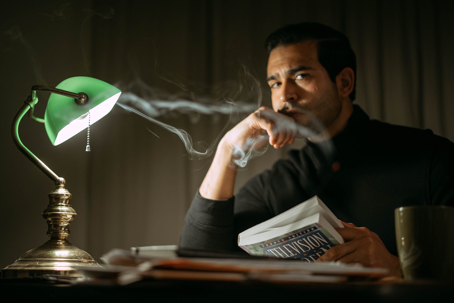 thoughtful man with book sitting in dark room
